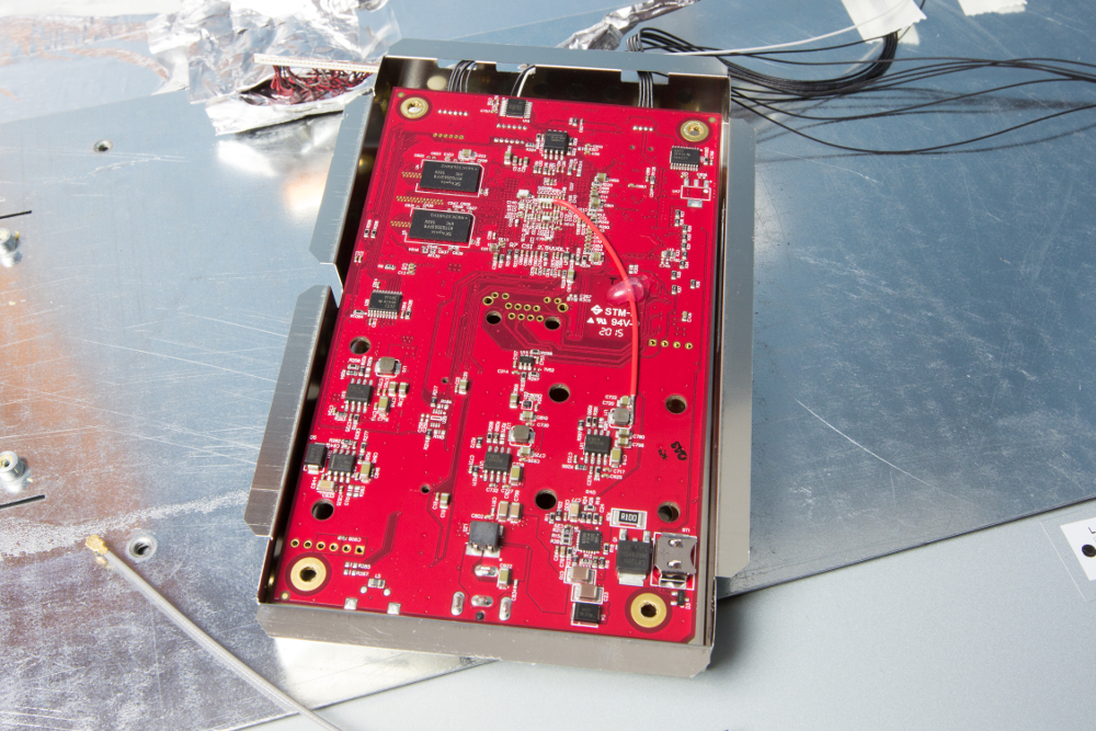 The frame's logic board photographed from below, shielding removed, connectors and flash storage visible.